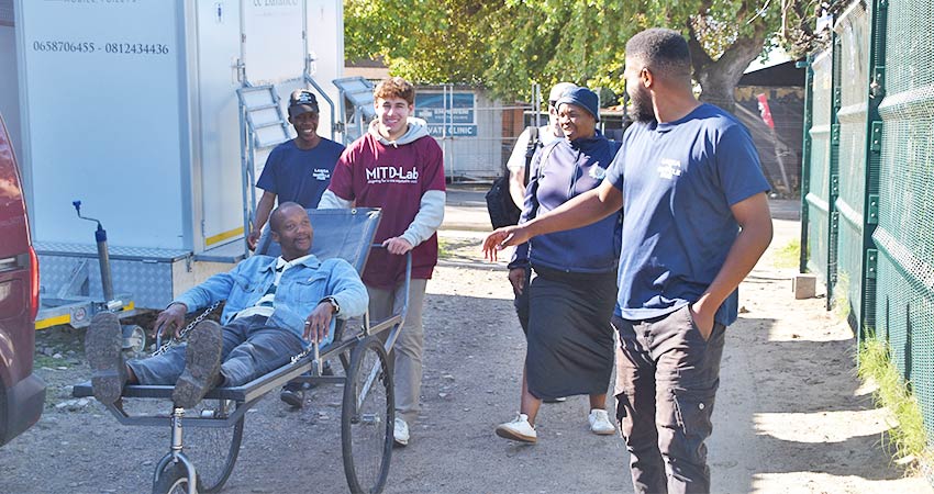 A Langa community member tests the stretcher prototype, pushed by a D-Lab student and accompanied by members of the Langa Bicycle Hub and Kheth’Impilo. Photo: Maddie Johnson-Harwitz