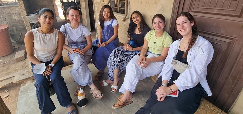 Six young women seated on benches.