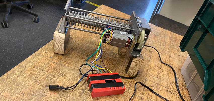 A modified paper shredder sitting on a workbench.