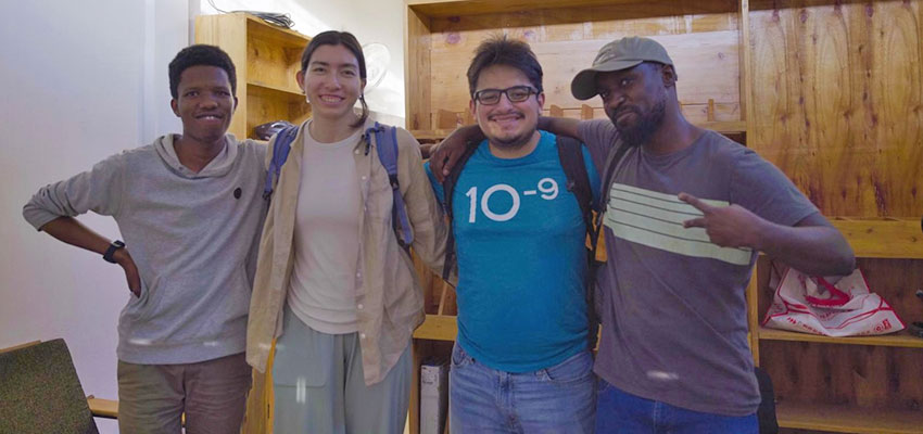 Four people - three men and one woman - standing, smiling, posing for photograph