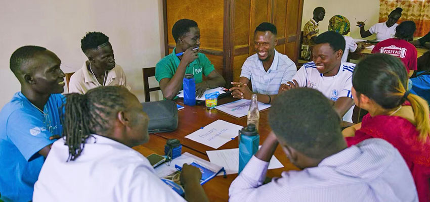 A group of people sitting around a table engage in an activity.